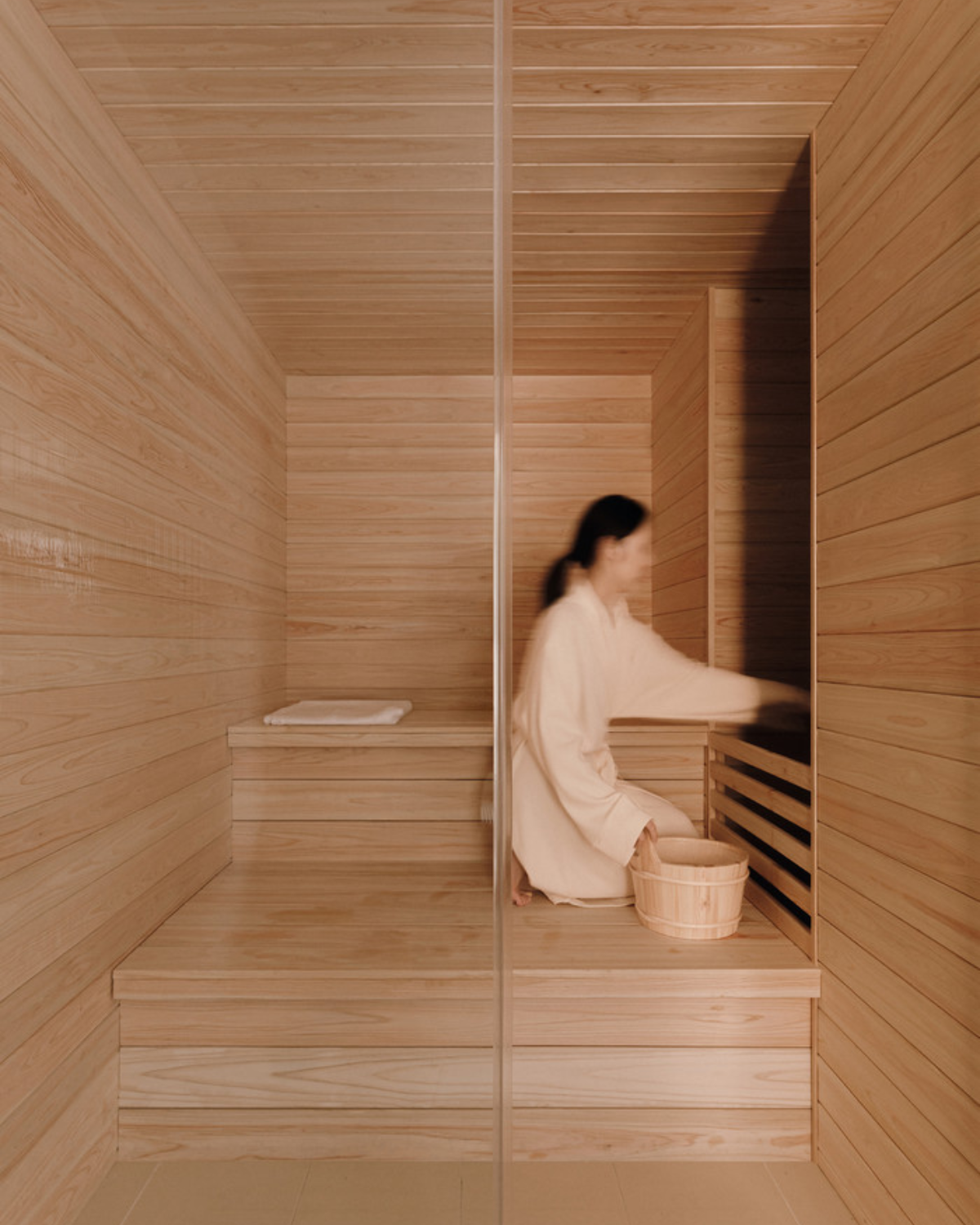A woman adding water to steam a sauna at Sisu House Seoul in Korea