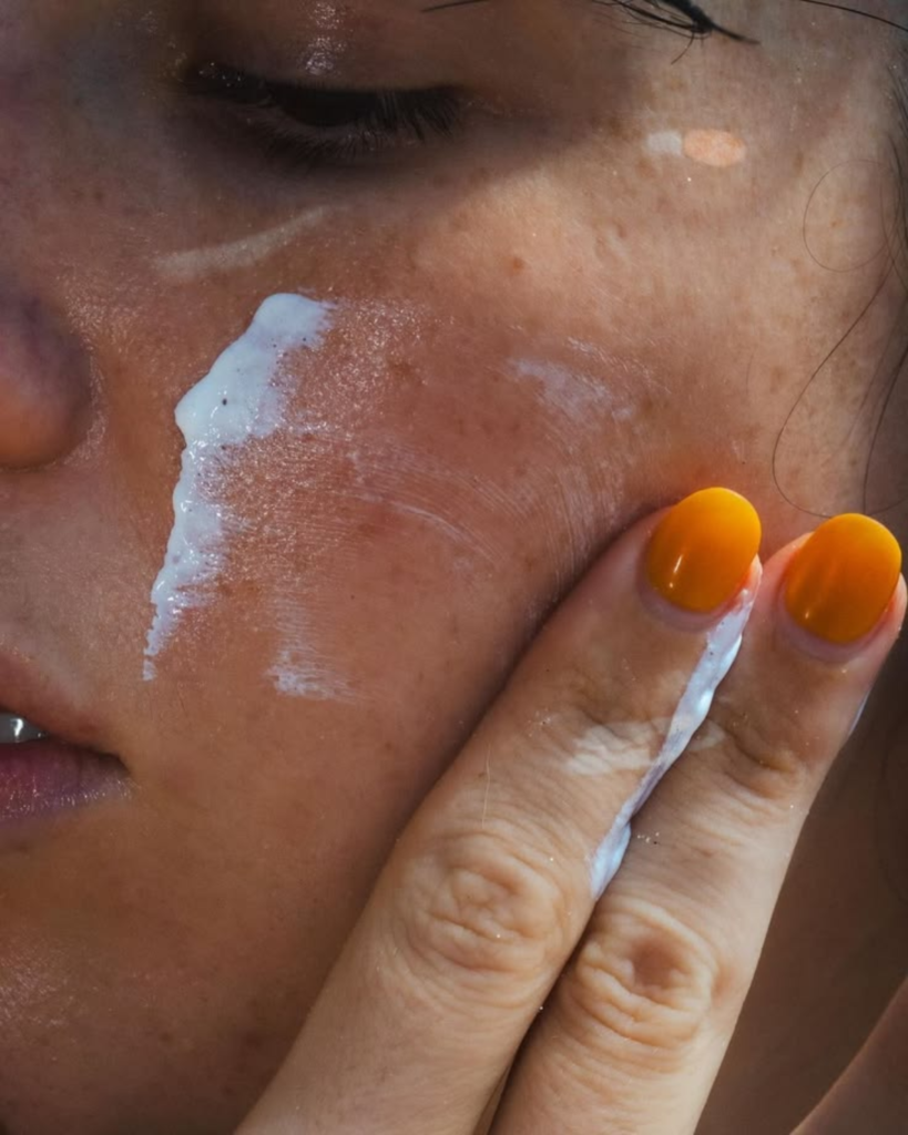 A woman applying sunscreen on her face